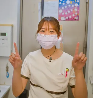 掲示板の前で、笑顔で指をさすスタッフ