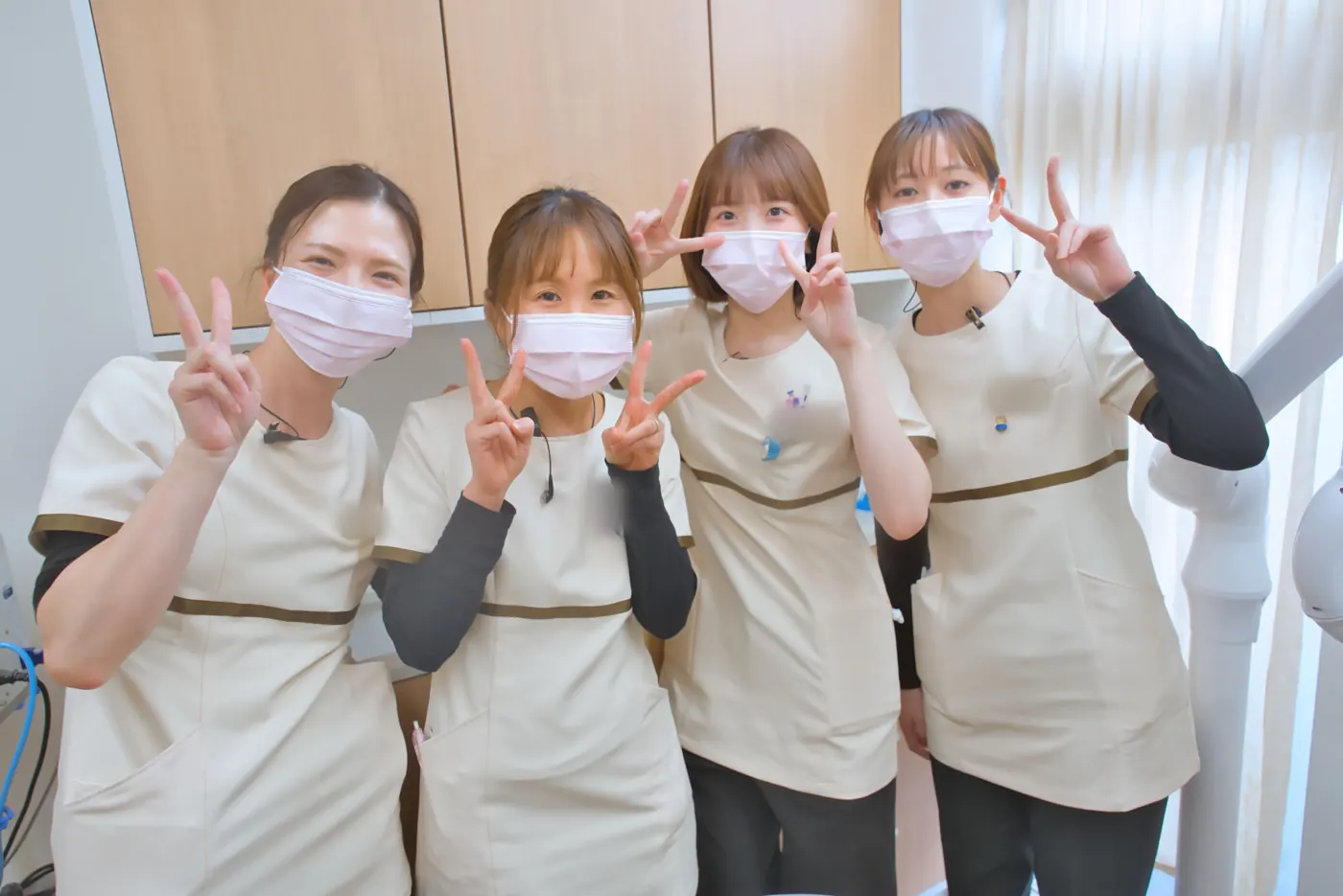 診療室で、ピースをして並ぶ歯科衛生士4人