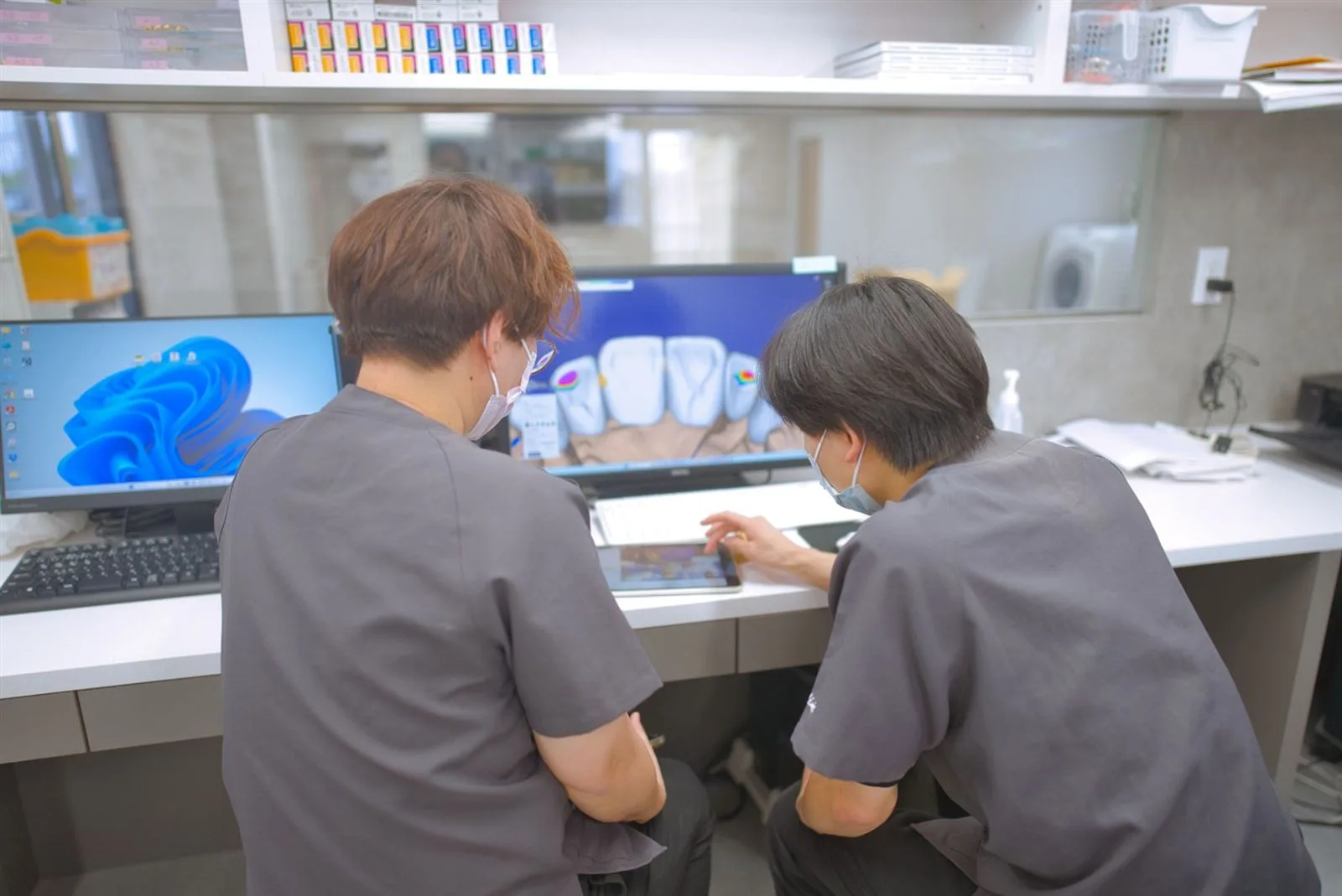2人でモニターの設計データを確かめる技工士