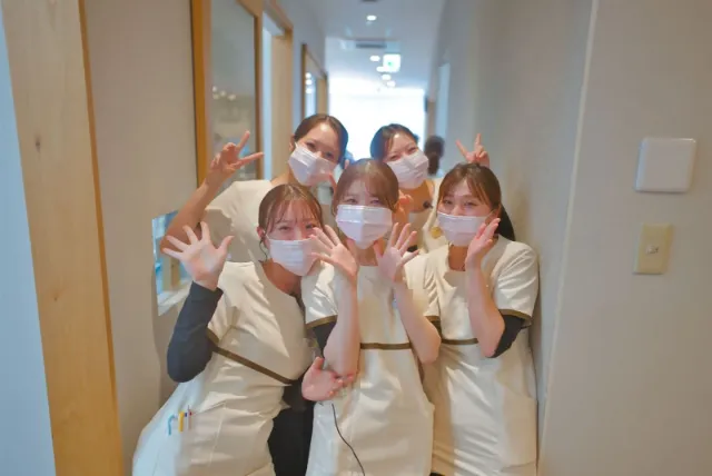 廊下で手を振るスタッフ5人