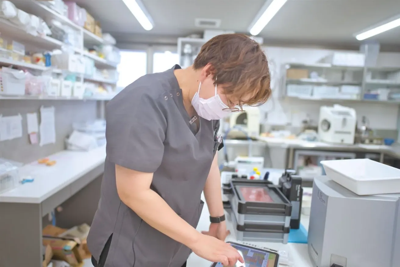 白を基調にした技工室でタブレットを確かめる技工士