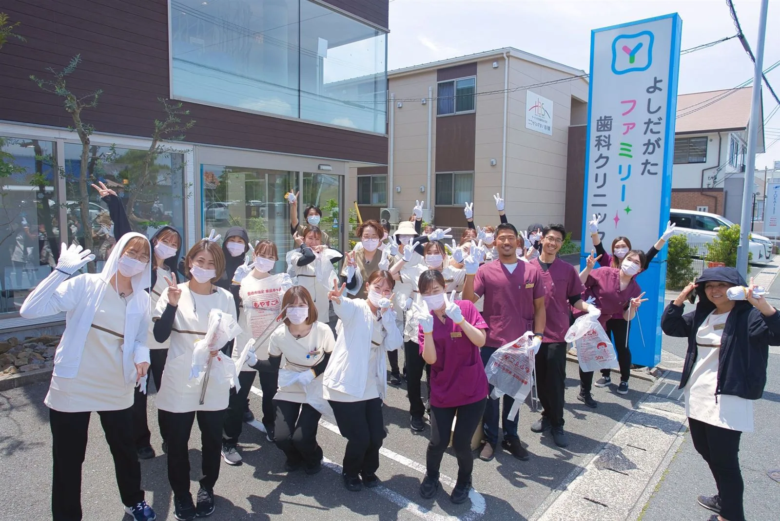 医院の看板の前に集まったスタッフたち