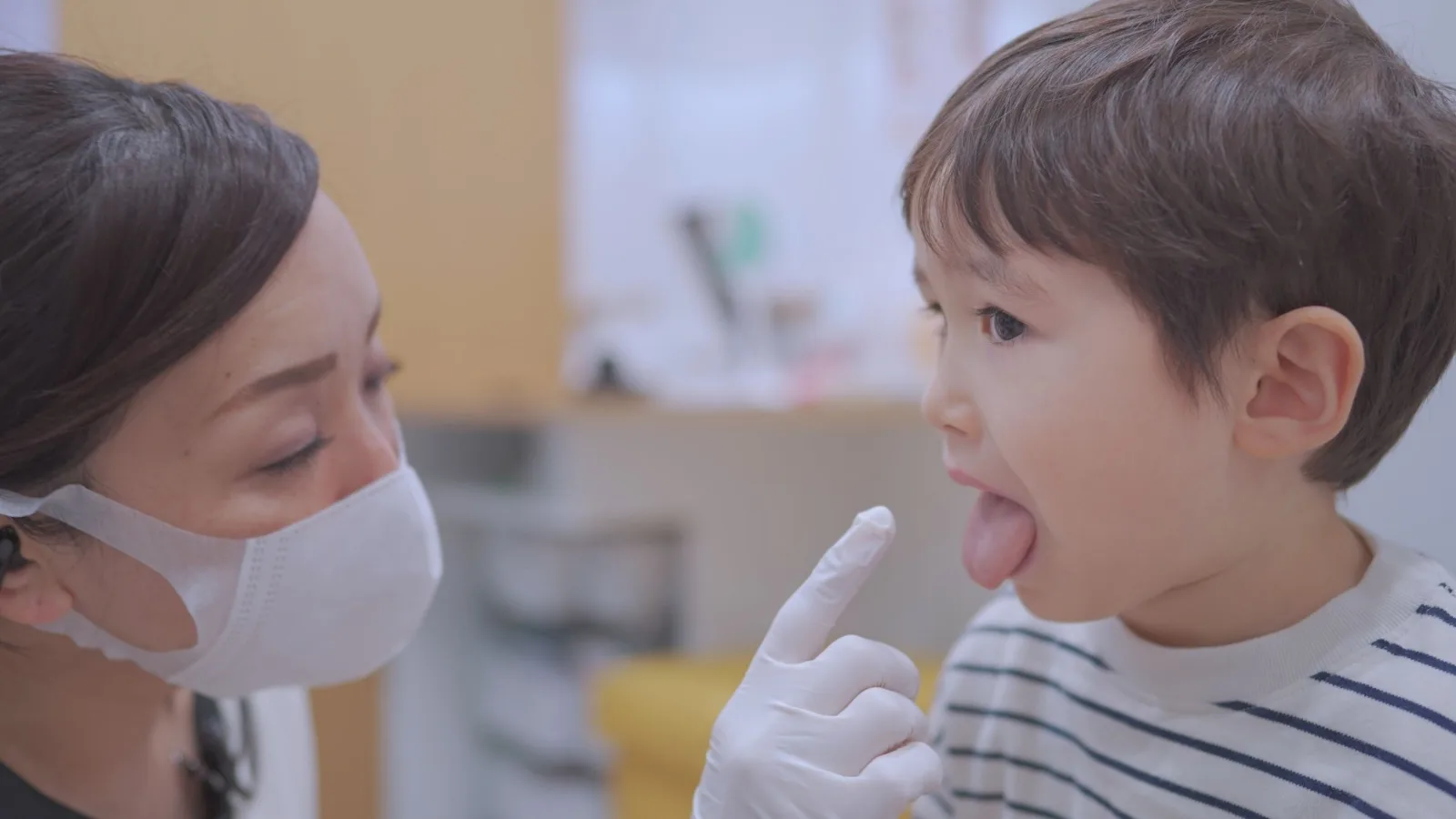 保育士が指で示しながら、子どもに舌の体操を教えている