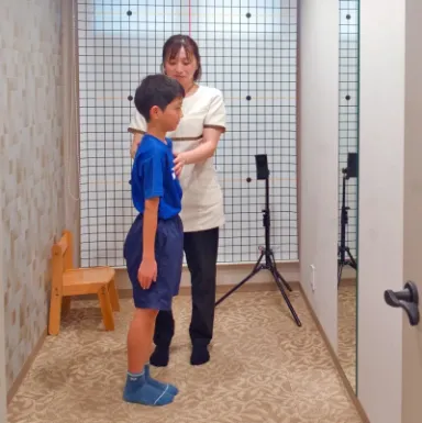 スタッフが子どもの体に手を添えて、立ち姿勢を確かめている