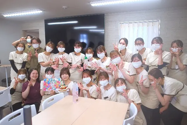 お祝いのケーキを囲んだ大人数の集合写真