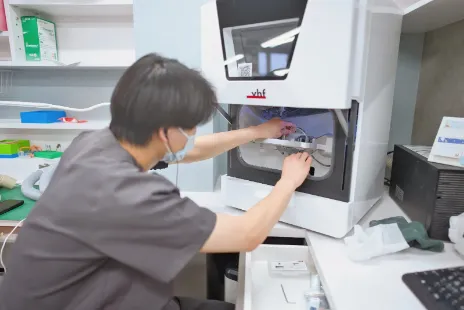 ミリングマシンに材料をセットする技工士